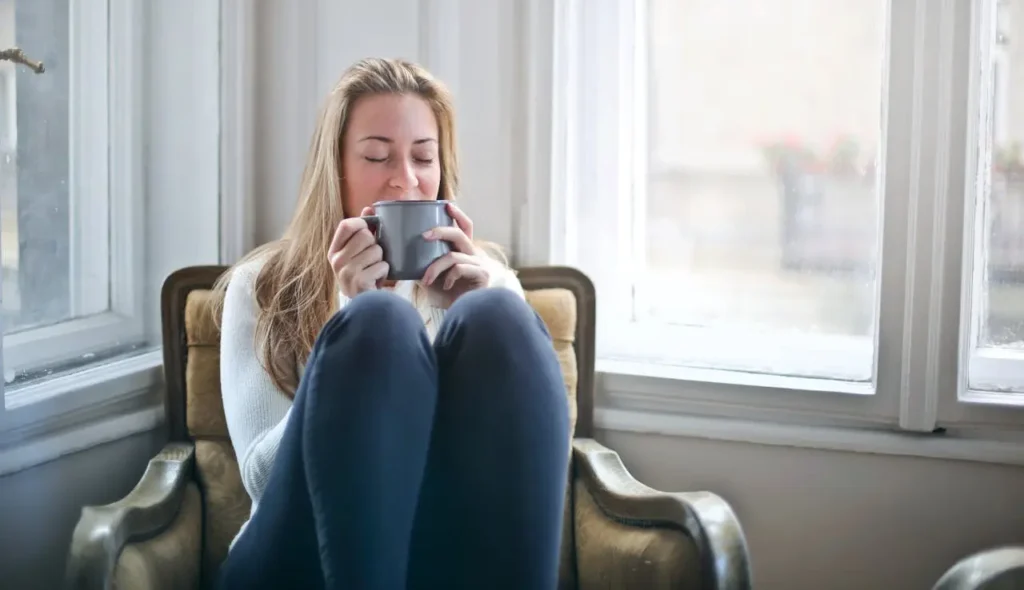 Woman enjoys morning coffee as part of self love routine.