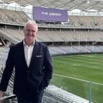 Former Australian television presenter Tim Gossage standing on the sidelines of a stadium.