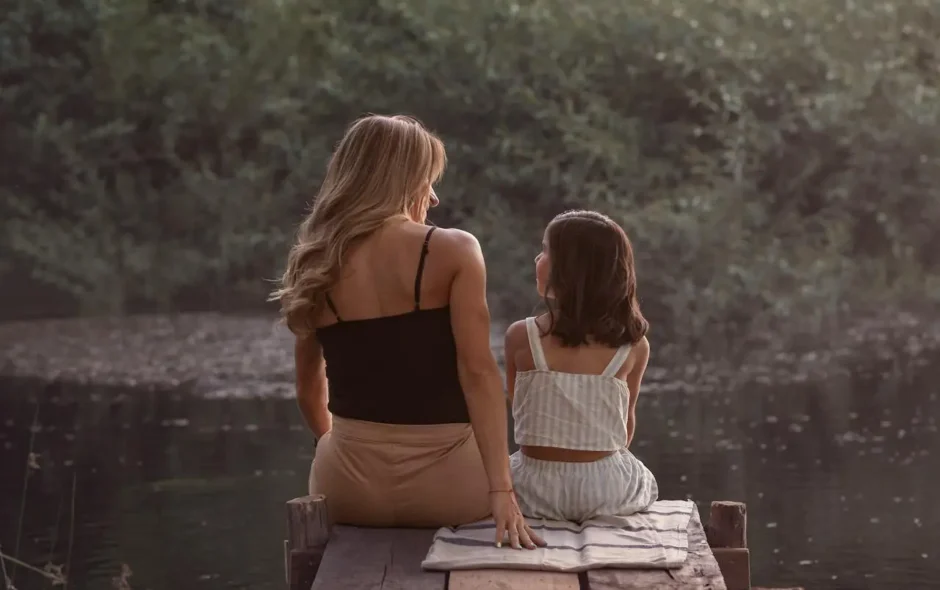 woman and daughter sitting at the end of a jetty
